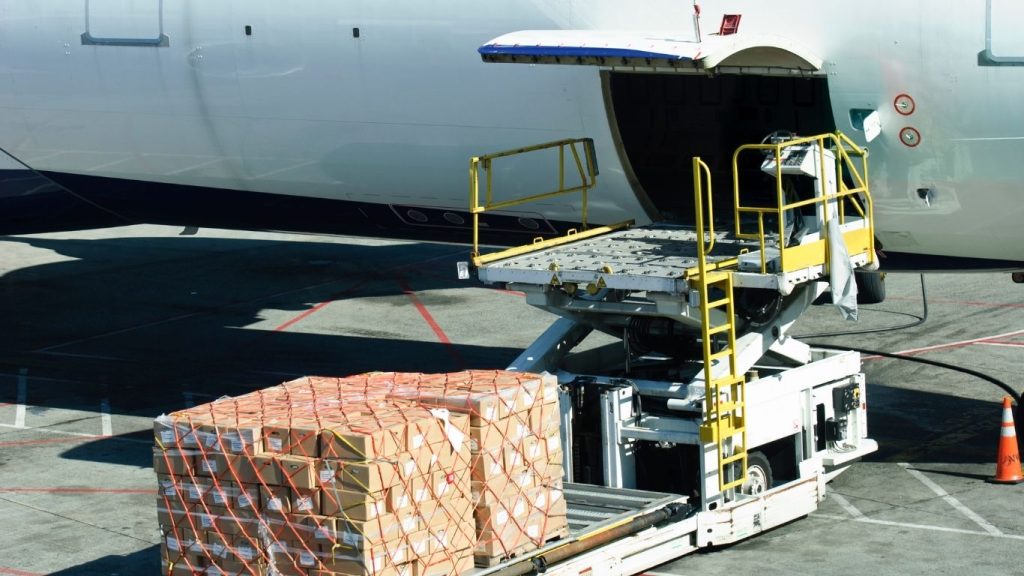 Carga sendo levada para dentro de área de carga de avião.