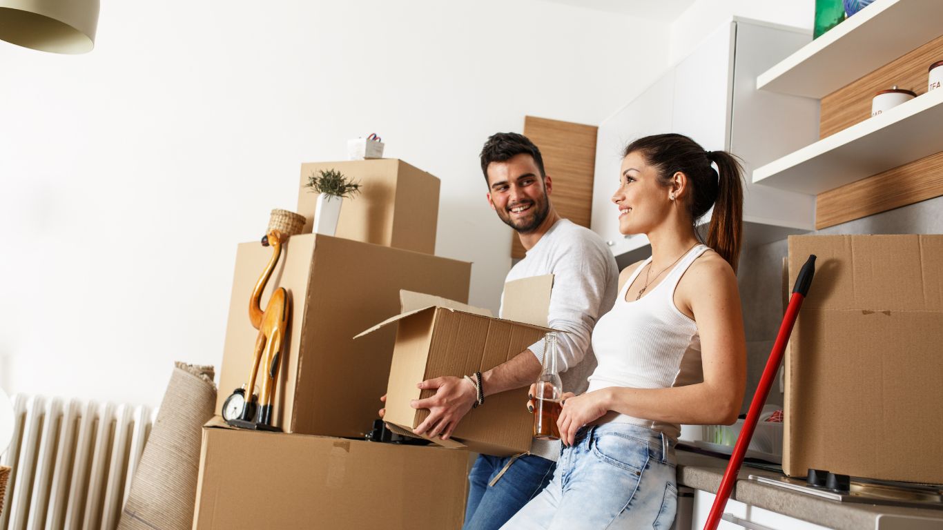 como organizar mudanças residenciais: casal conversando em meio a caixas de mudança espalhadas por cômodo.